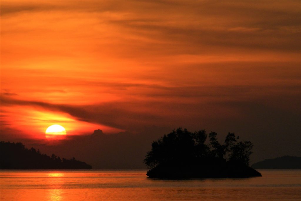 Red-golden sun going down behind little island in Raja Ampat
